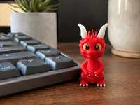 Flamy le Petit Dragon Bougon - figurine miniature 5cm sur un clavier d'ordinateur